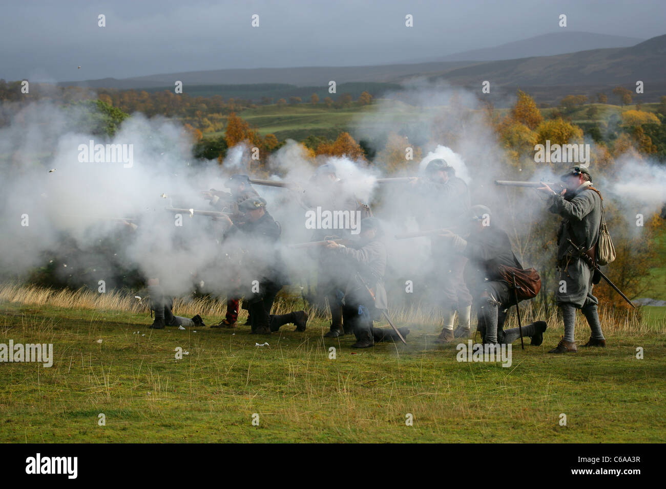 Members of [Fraser's Dragoons], a 17th century re-enactment society, obscured by the smoke from a volley of musket fire Stock Photo
