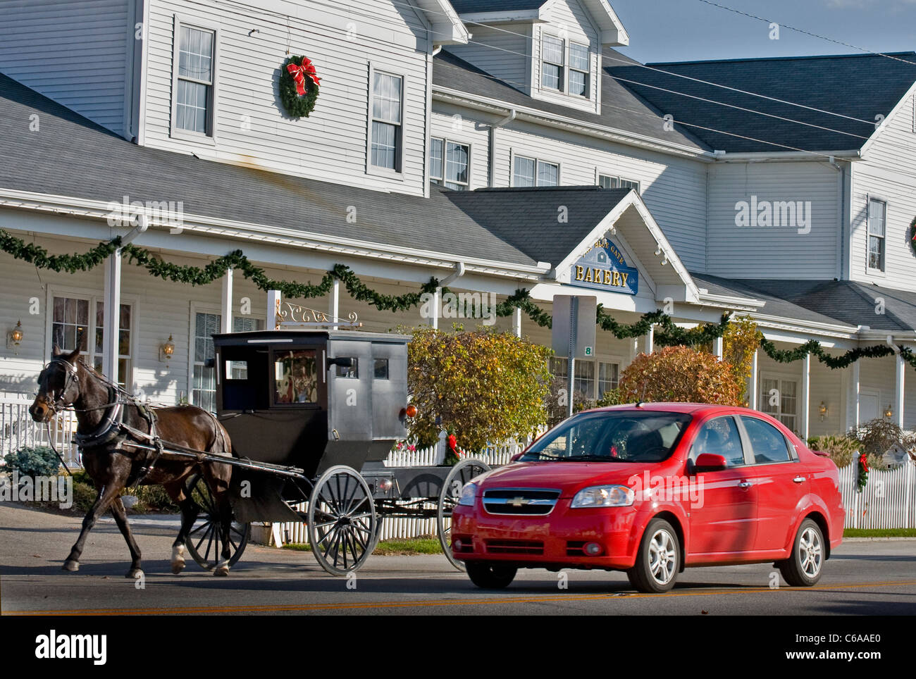 car and Amish buggy  passing by the famous Blue Gate Restaurant and Bakery, popular for its Amish food, in Shipshewana, Indiana. Stock Photo