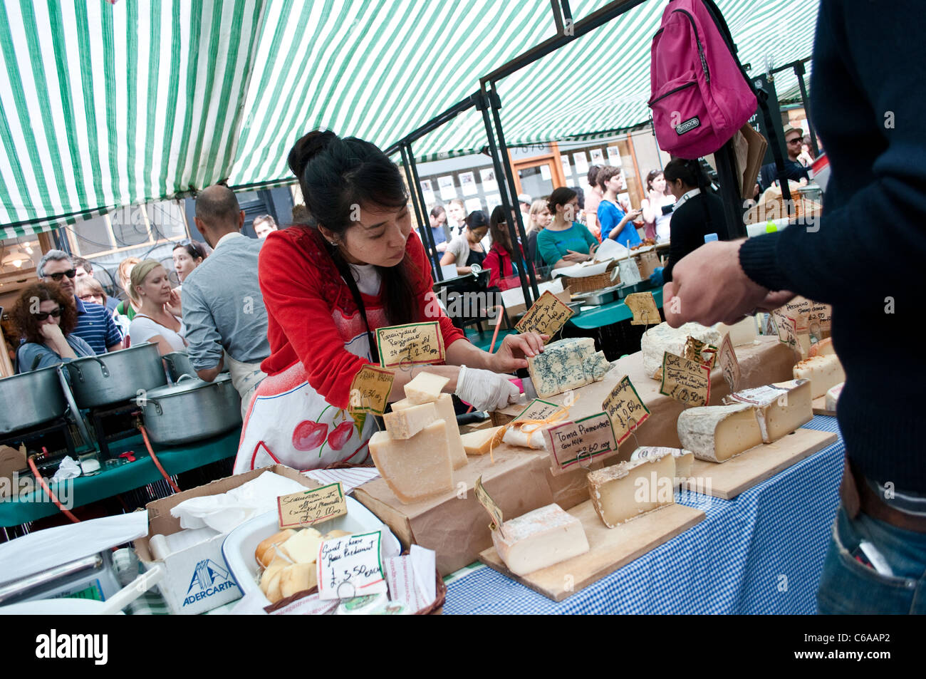 Woman trader cutting cheese, Broadway Market, Hackney, London, UK Stock Photo