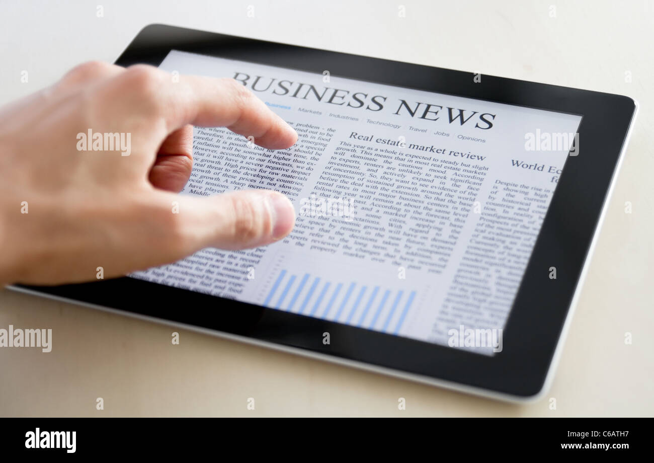 Man hands are pointing on touch screen device with business news. Stock Photo