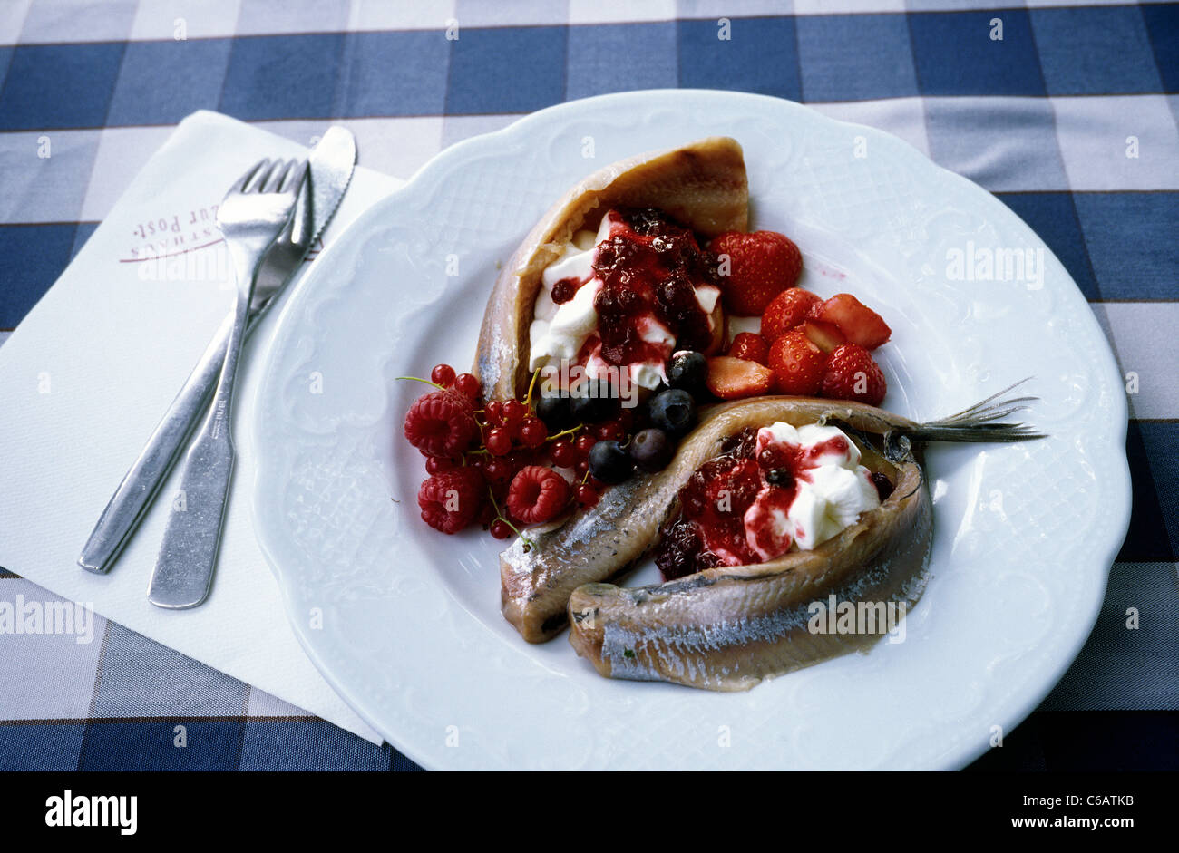 Dish of Matjes (soused herring) served with a variety of berries in a restaurant in Cranz near Hamburg. Stock Photo
