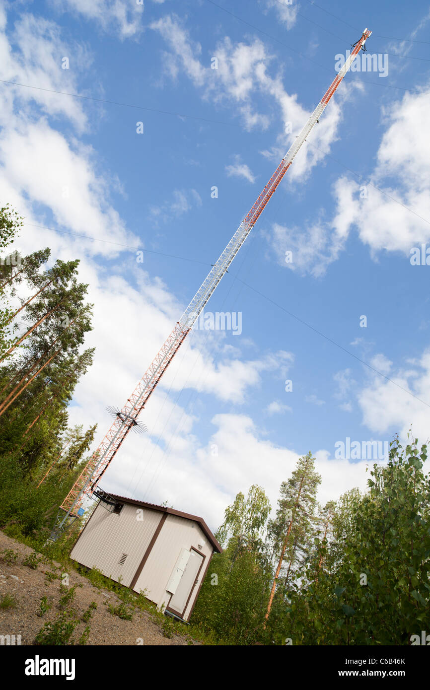 Cellular base station building with equipment and power supply and a tall mast for antennas at countryside , Finland Stock Photo