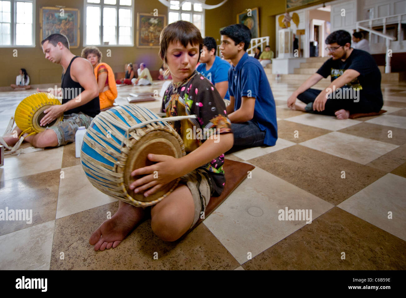 Worshipers chant while a boy plays the playing on a harmonium and a 'Mirdanga' drum during services at a Hindu temple in Laguna Stock Photo