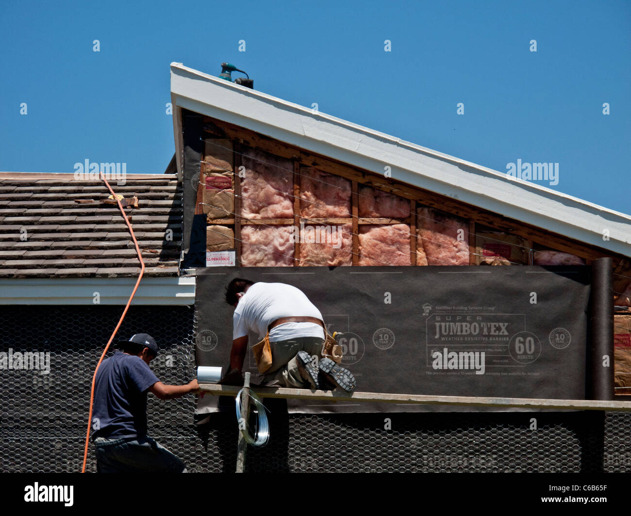 Hispanic workmen install tarpaper on a home exterior in Laguna Niguel ...
