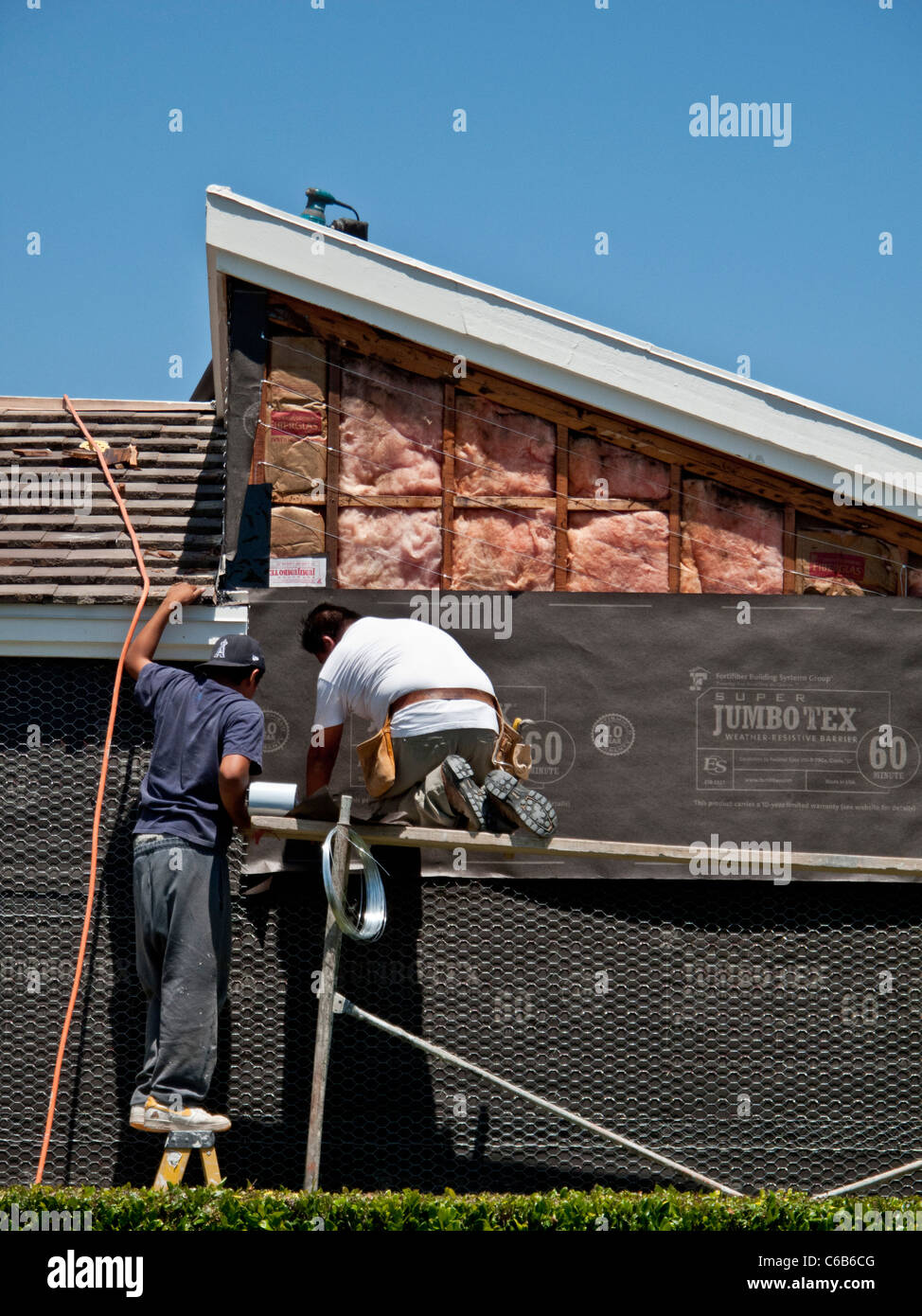 Hispanic workmen install tarpaper on a home exterior in Laguna Niguel ...