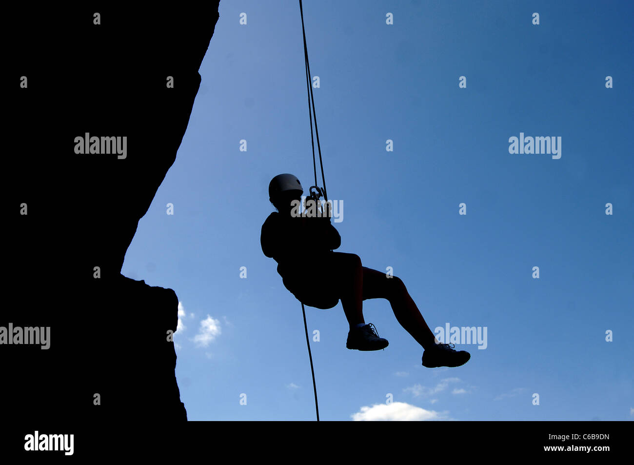 silhouette of a person Rappelling, an outdoor sport that requires  descending a steep rock during a rock climbing event Stock Photo - Alamy