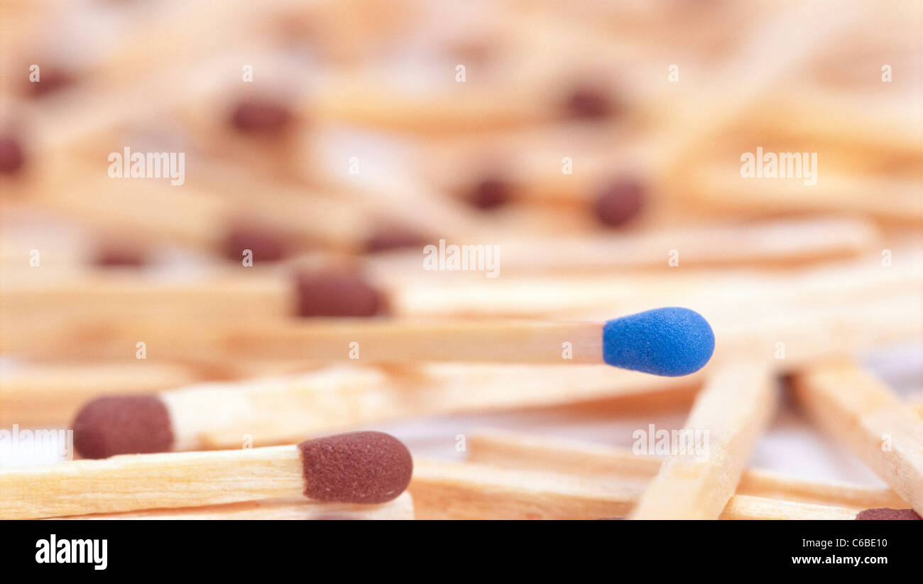 Strewn brown-tipped safety matches with a blue one standing out. Stock Photo