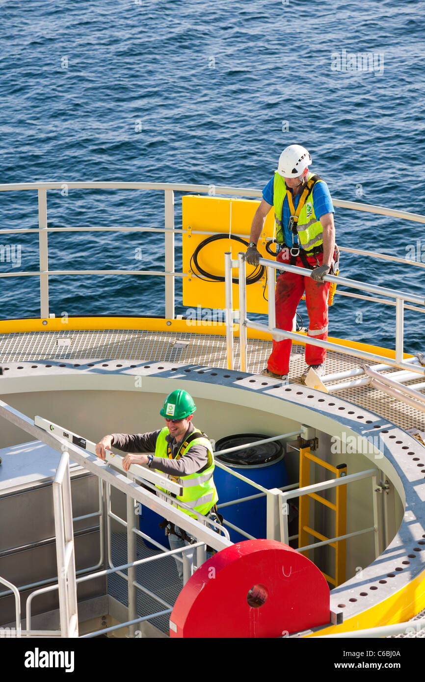 Workers check the level of a transition piece that the jack up barge, Goliath lifted into place on the Walney Offshore windfarm Stock Photo