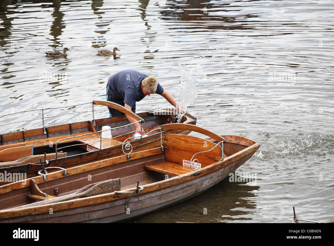 Young man bailing water out of rowing boat, Derwent water, Keswick, Cumbria, North West England, UK Stock Photo