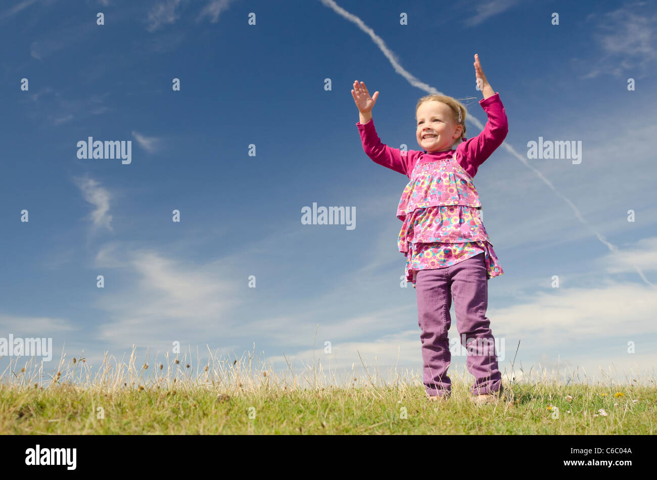 Happy little girl jumping in front of blue sky Stock Photo - Alamy