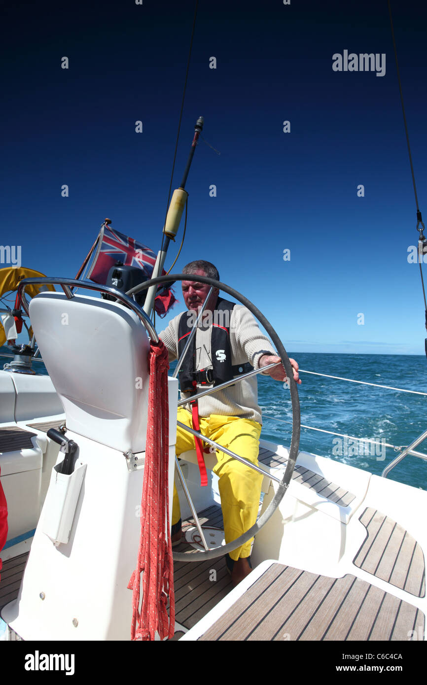 man at the helm of a sailing yacht in blue sky weather Stock Photo Alamy