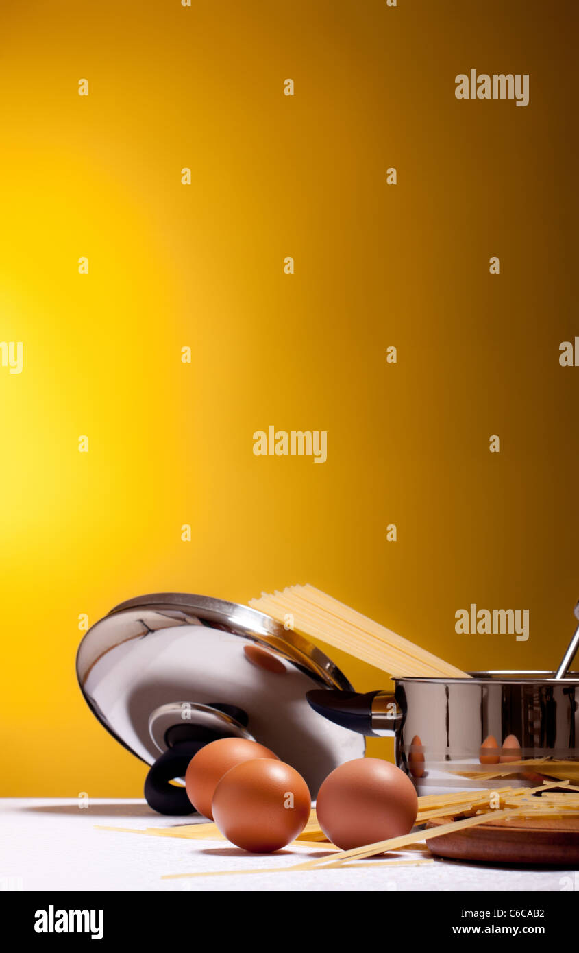 spaghetti, eggs, cheese and utensils on table Stock Photo