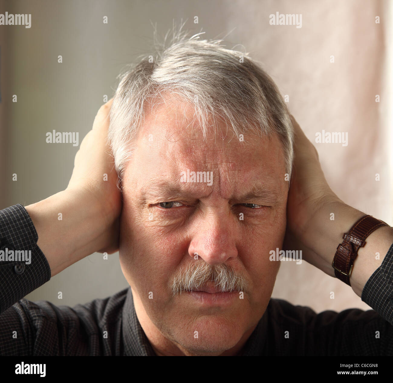 older man shows irritation at loud noises Stock Photo