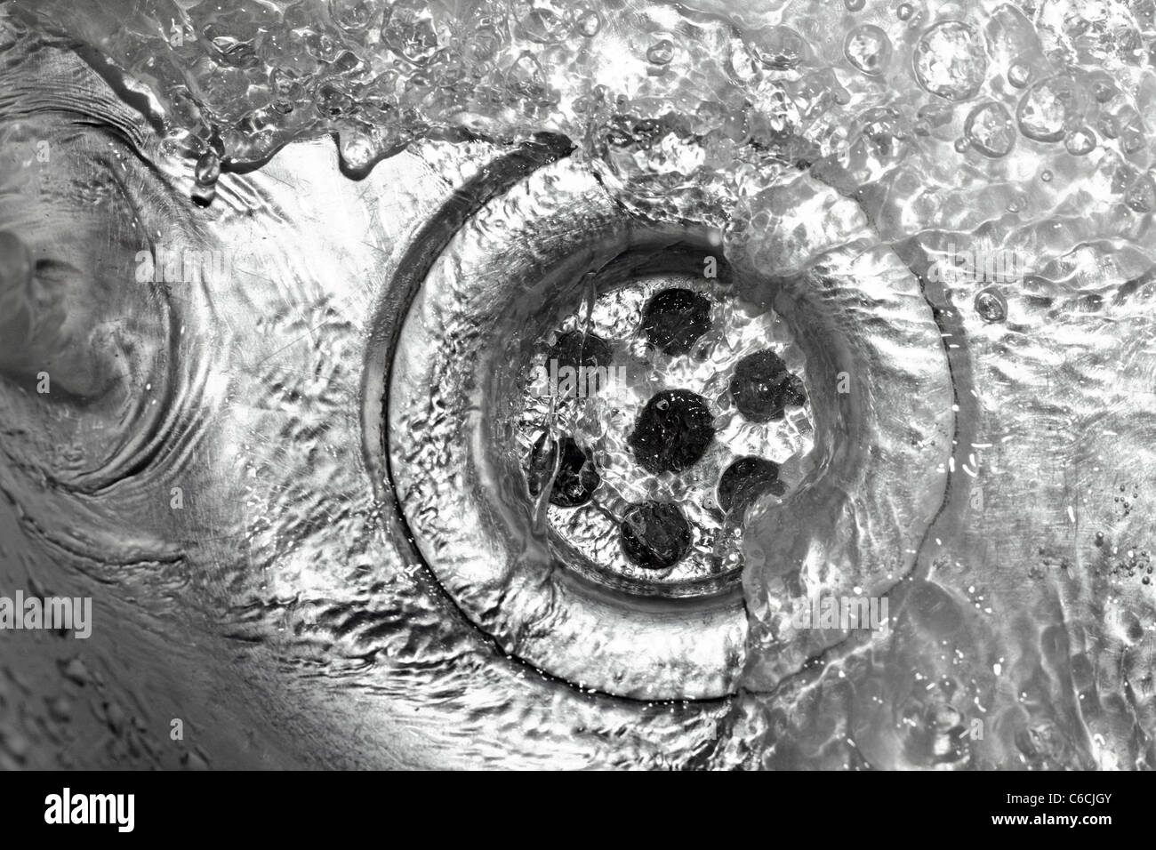 Metallic Kitchen sink swirly water flow and drops shot from above Stock