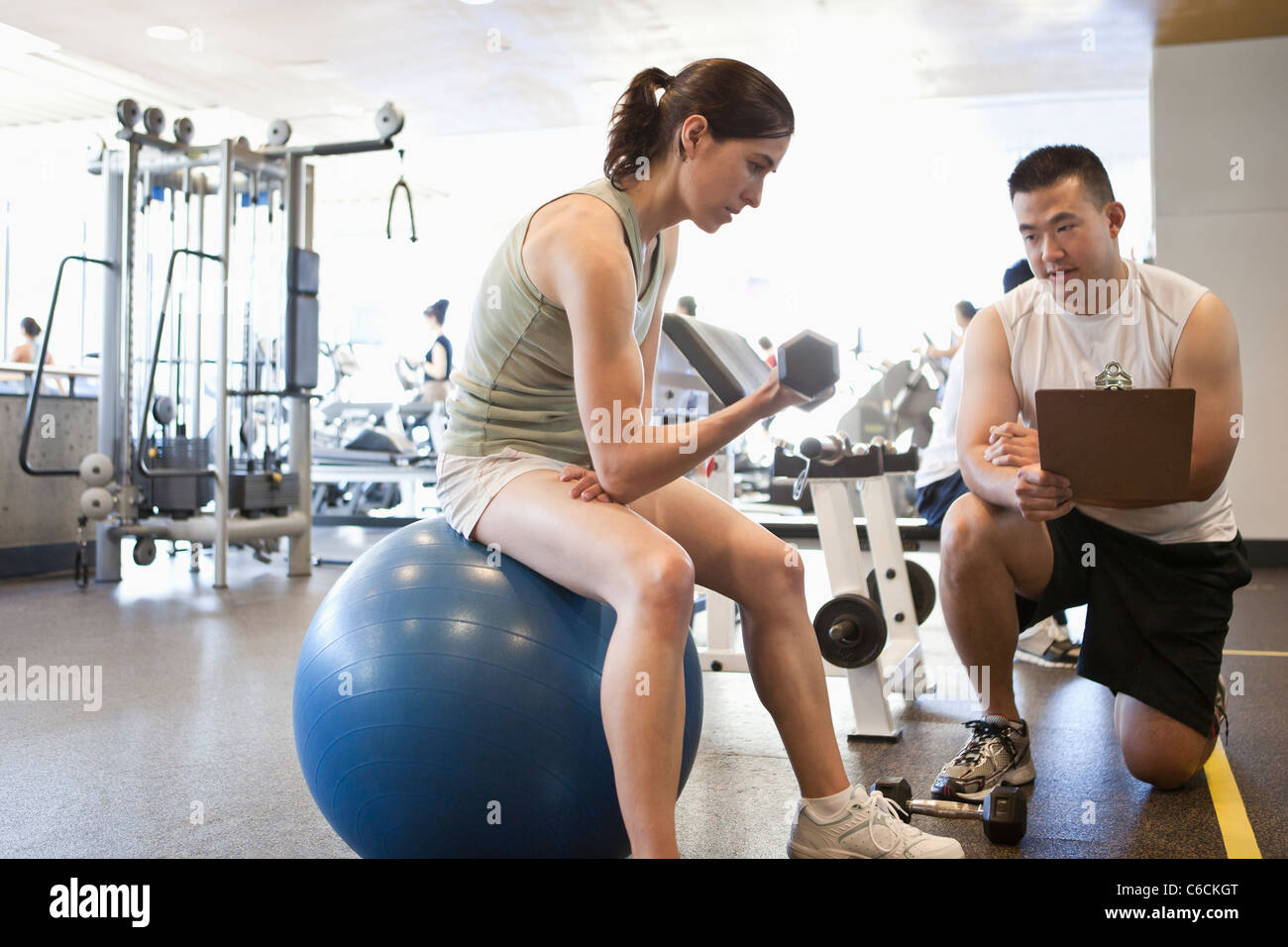 Woman working with personal trainer in health club Stock Photo