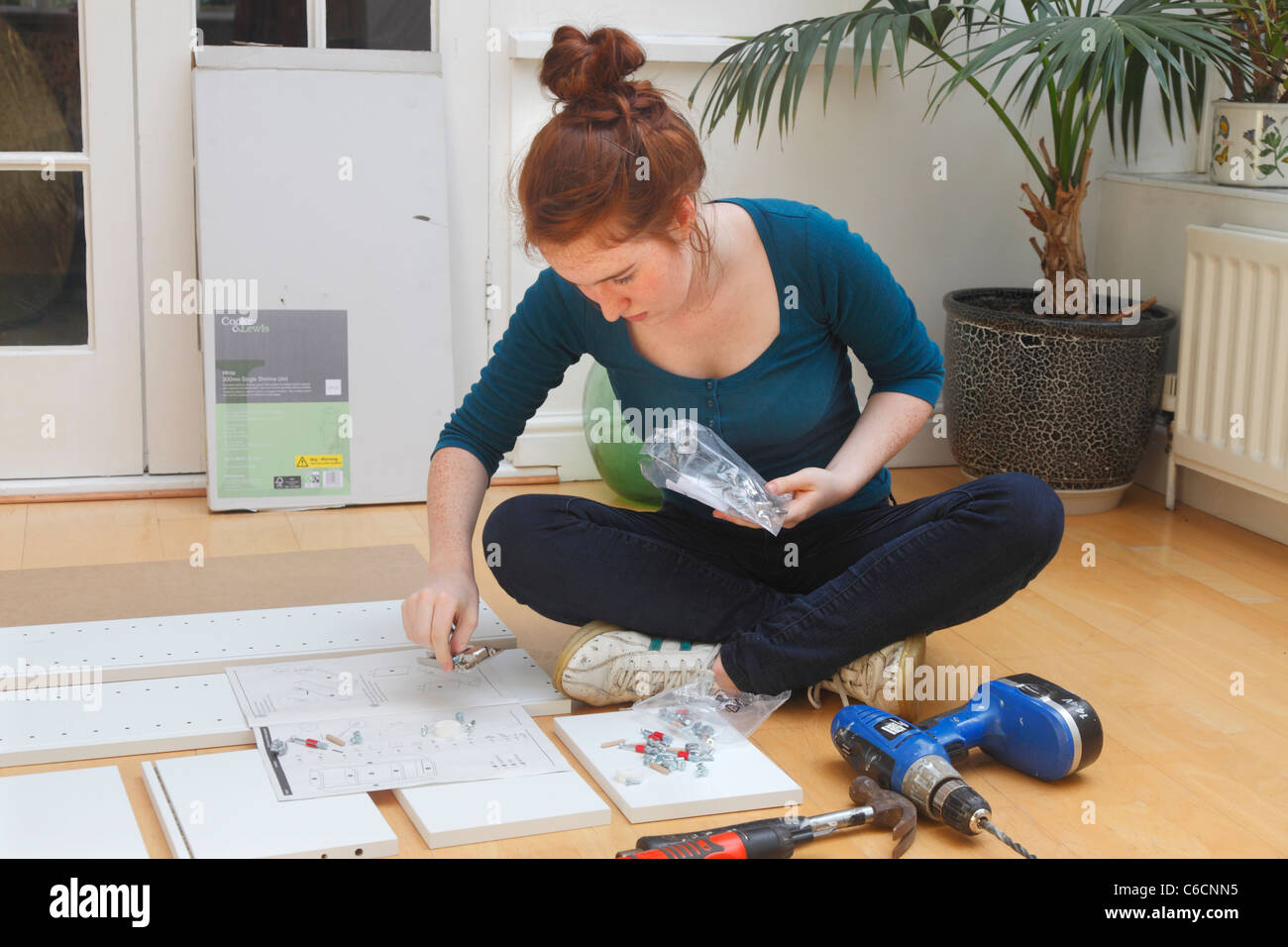 Young girl making a cabinet from a 'flat Pack' DIY kit. Stock Photo