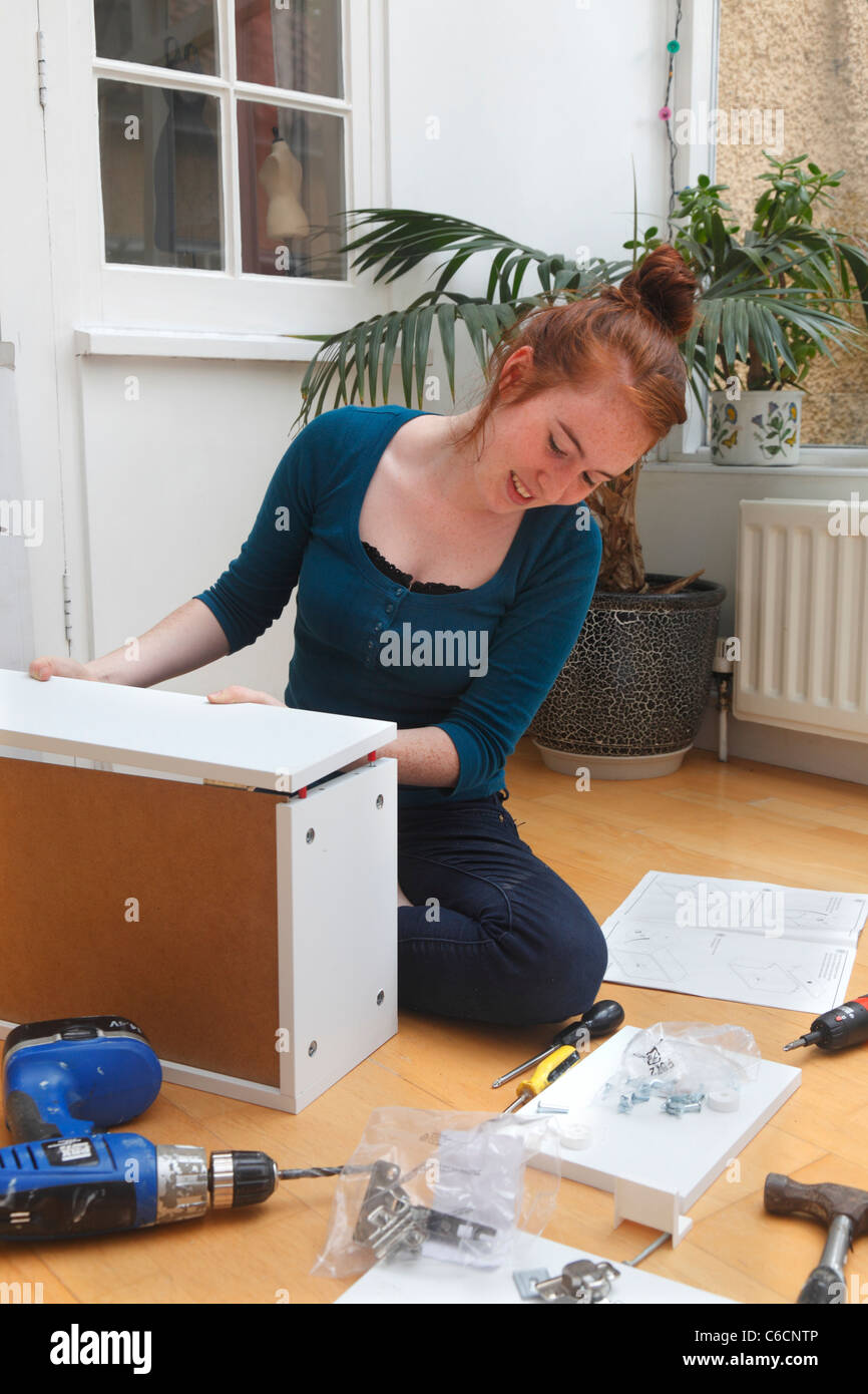 Young girl making a cabinet from a 'flat Pack' DIY kit. Stock Photo