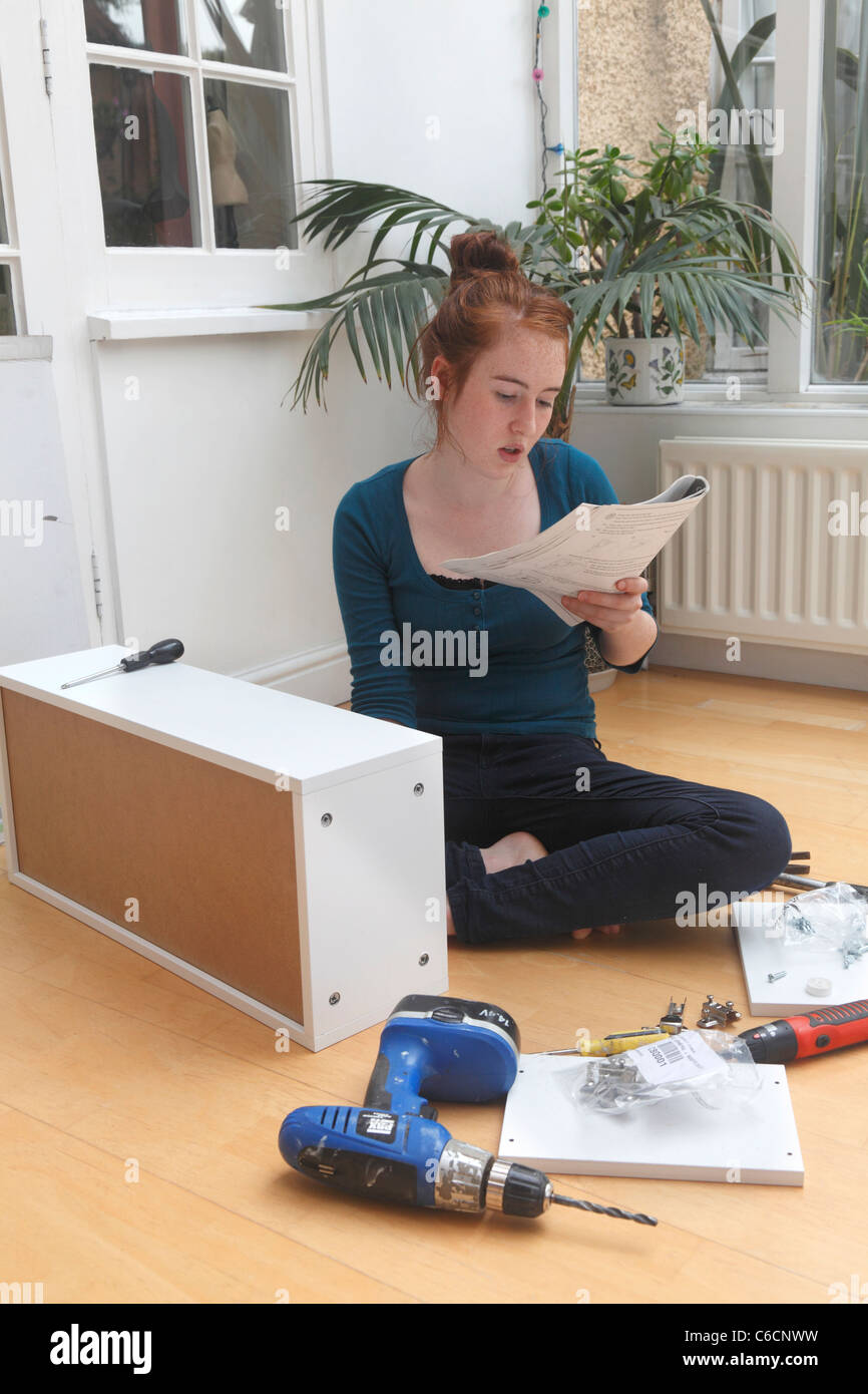 Young girl making a cabinet from a 'flat Pack' DIY kit. Stock Photo