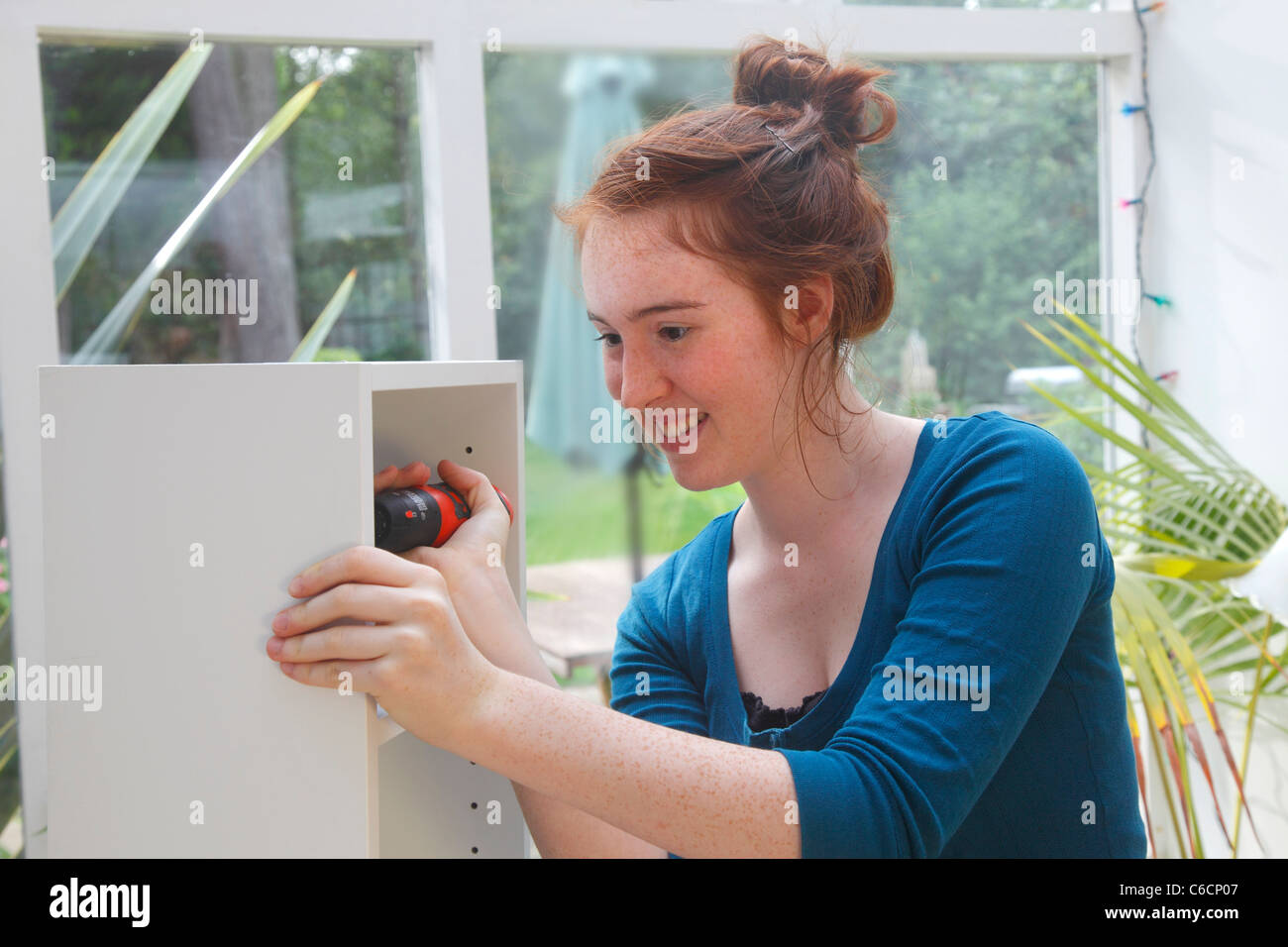 Young girl making a cabinet from a flat pack DIY kit. Stock Photo