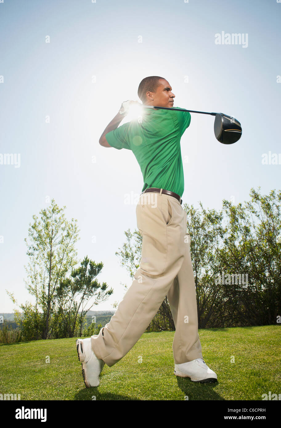 Black golfer swinging golf club Stock Photo
