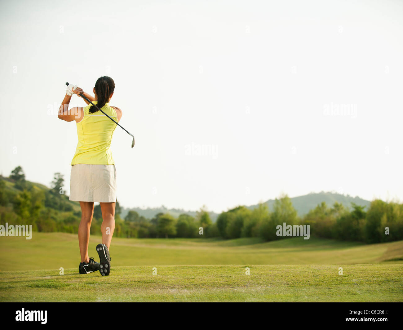 Mixed race woman swinging golf club on golf course Stock Photo Alamy