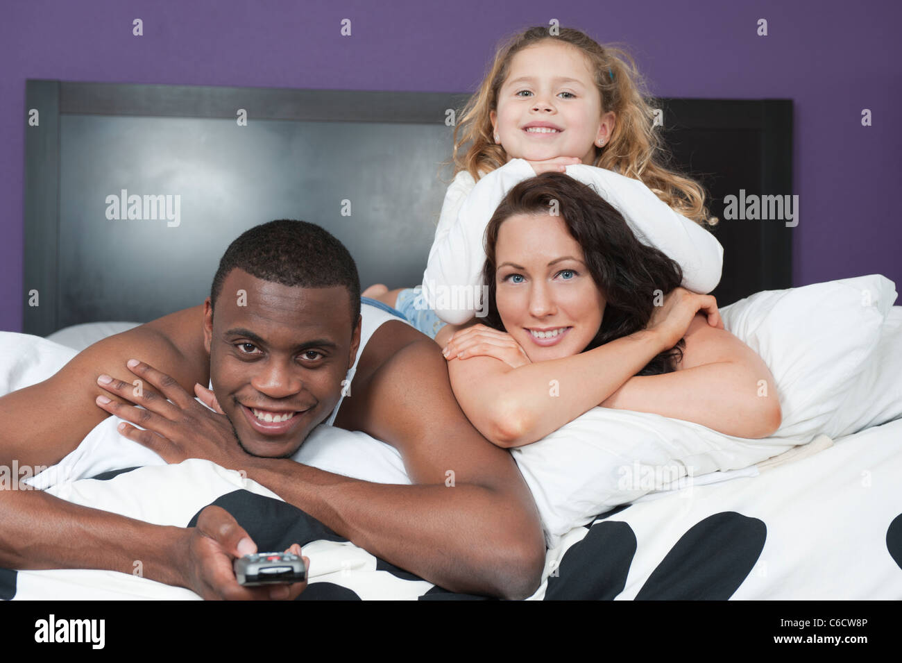 Family laying in bed together watching television Stock Photo Alamy