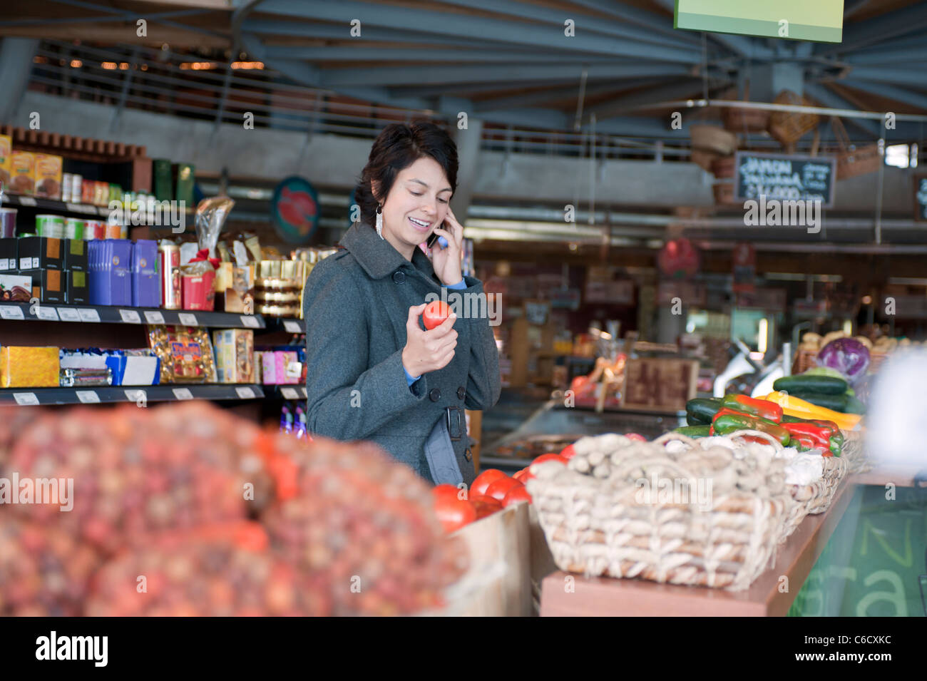 Hispanic woman talking on cell phone and shopping in grocery store Stock Photo
