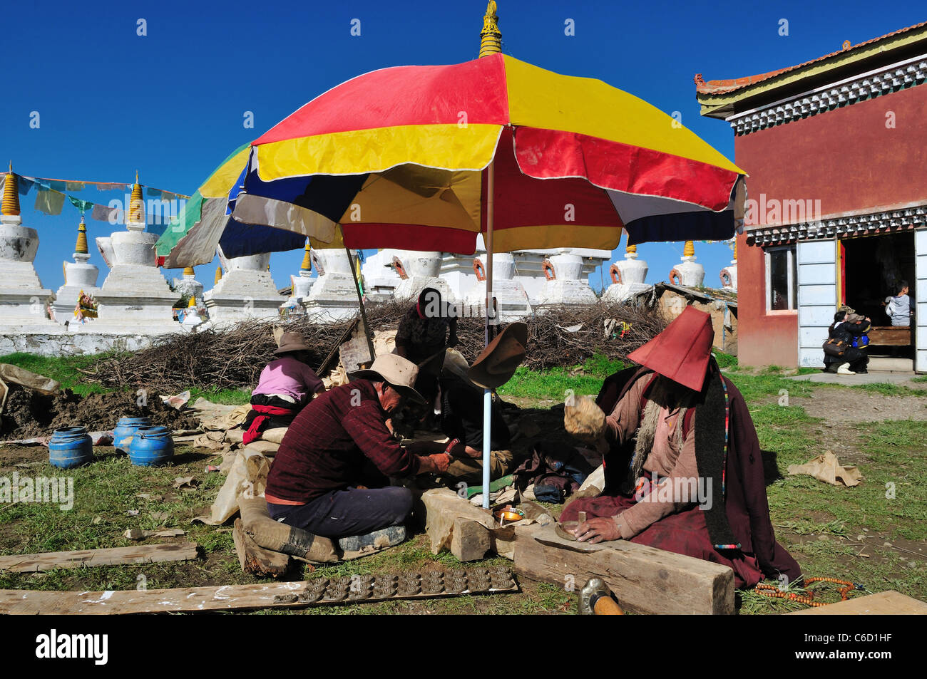 Local Tibetans making clay offering tablets at a Buddhist temple. Sichuan, China. Stock Photo