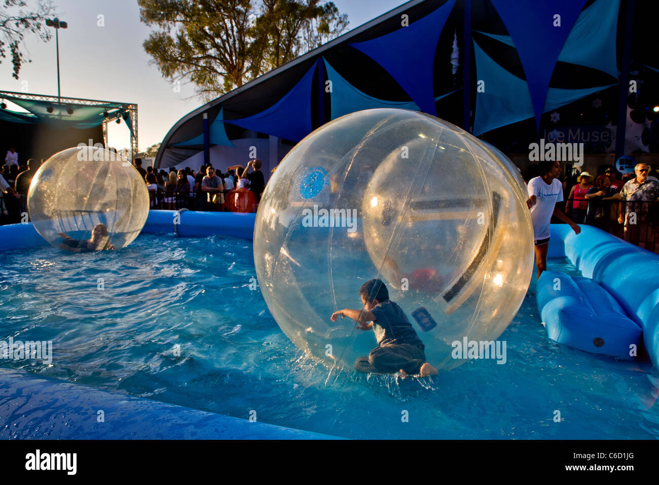 Hispanic children float on a pool in plastic spheres at an amusement