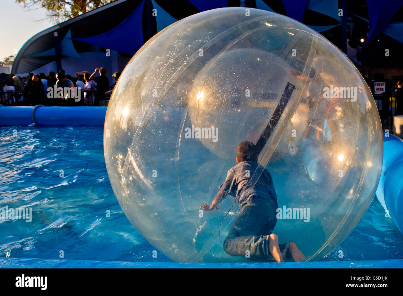 Hispanic children float on a pool in plastic spheres at an amusement