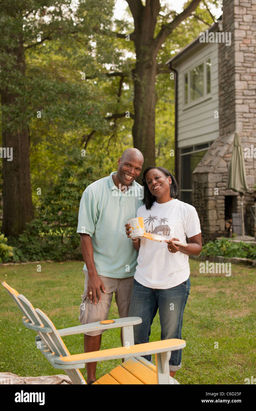 African American couple painting chair in backyard Stock Photo