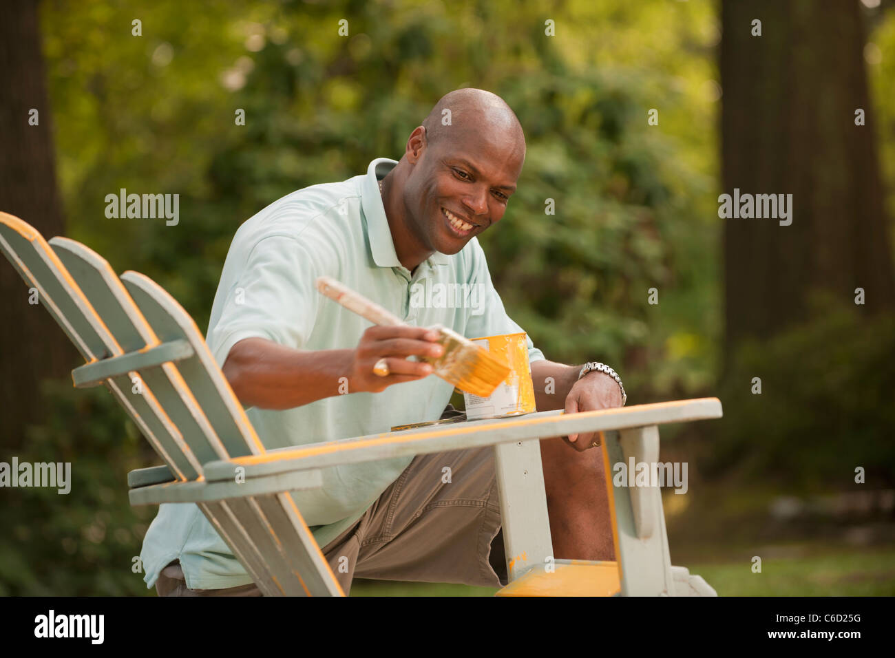 African American man painting chair in backyard Stock Photo