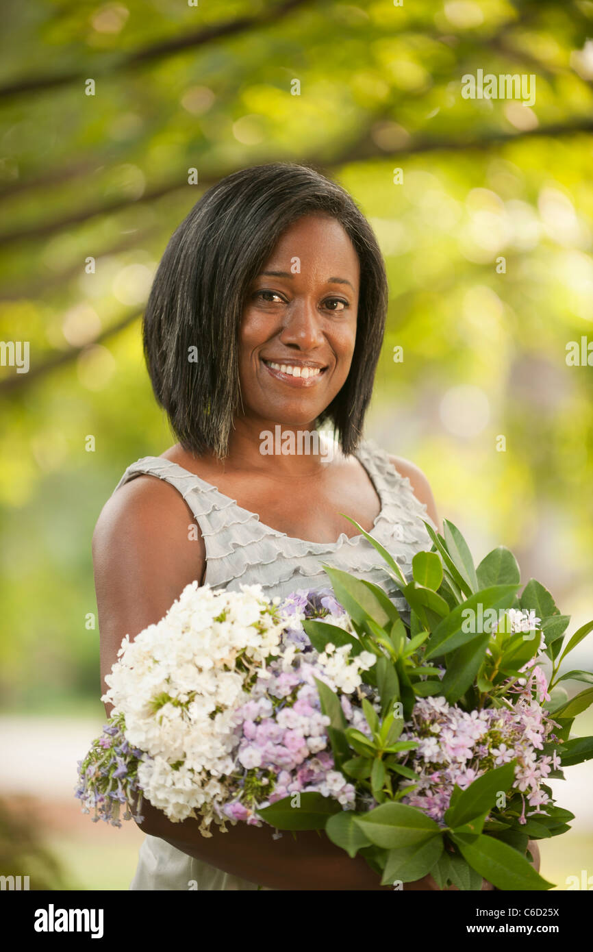 Smiling African American woman holding bouquet of flowers Stock Photo ...