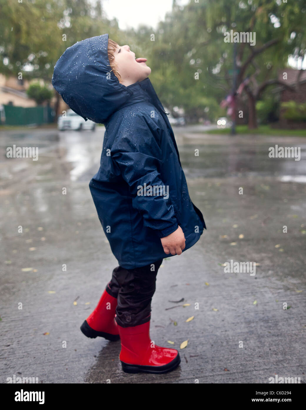 Caucasian boy catching raindrops on tongue Stock Photo