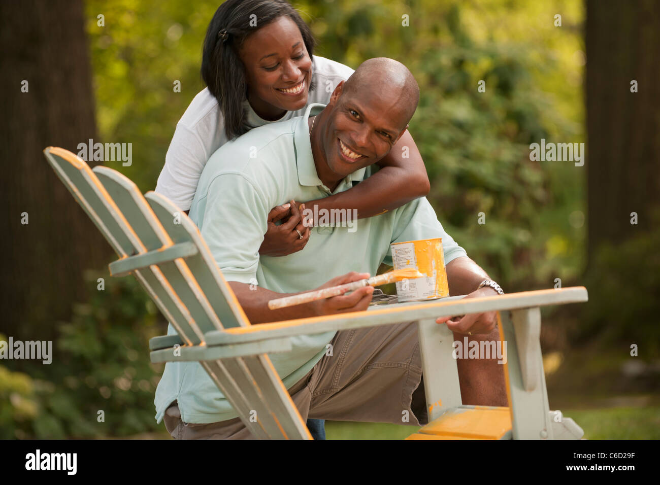 African American couple painting chair in backyard Stock Photo