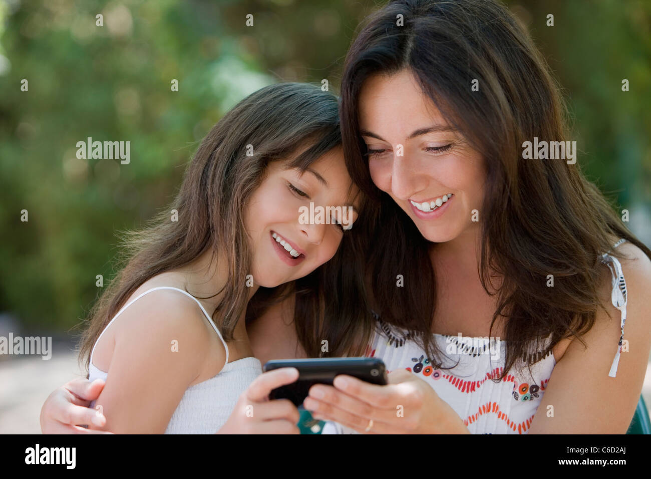 Hispanic mother and daughter text messaging on cell phone Stock Photo ...