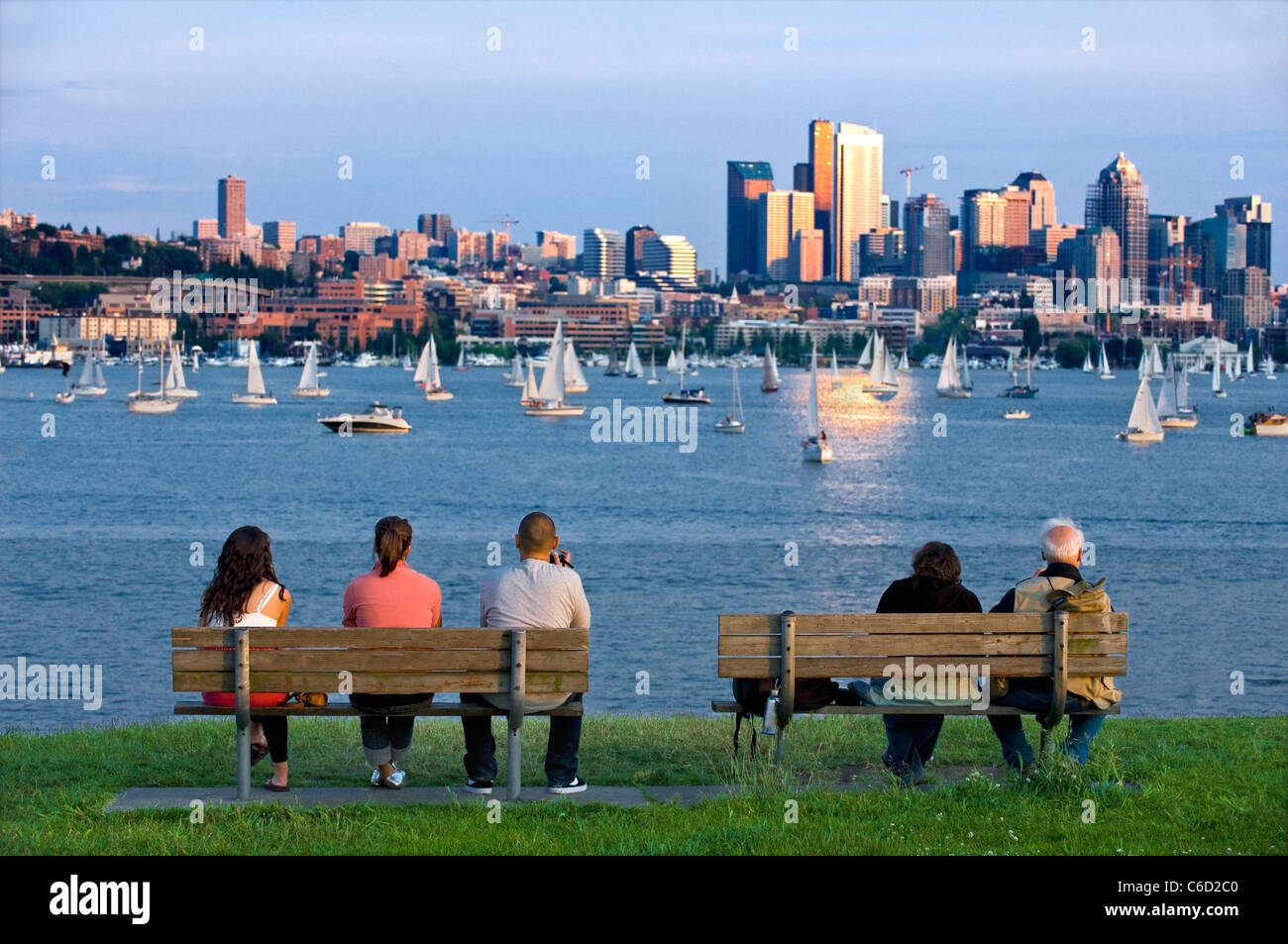 People setting on benches watching sailboats on Lake Union, Seattle, Washington, USA Stock Photo