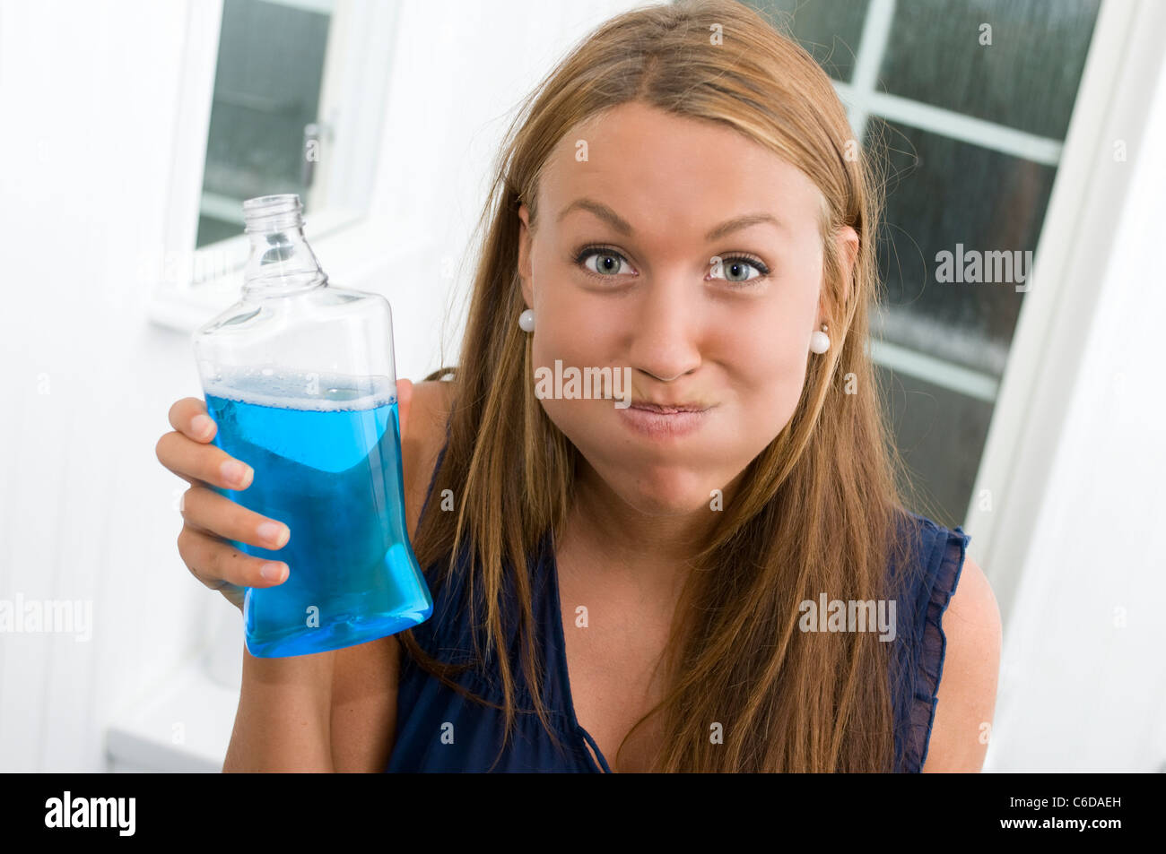 Young Woman With Mouth Full Of Blue Mouthwash Stock Photo