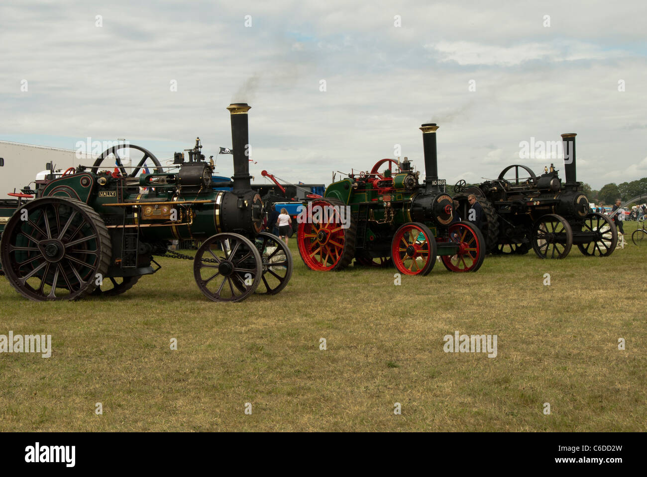 Three steam traction engines lined up in a field, shows smoke coming from the funnels of the engines, with detail in the sky Stock Photo