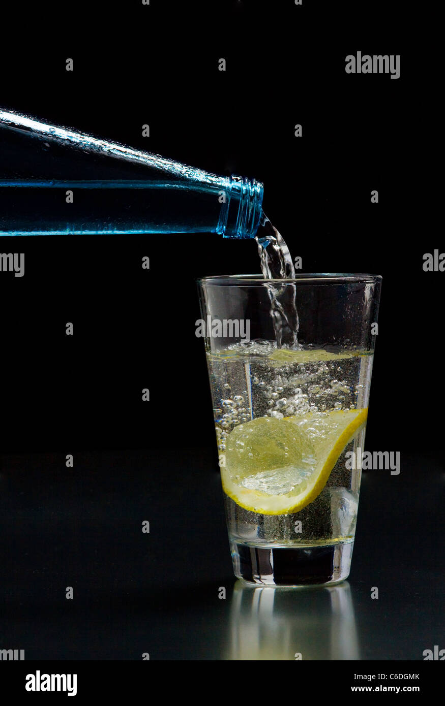 Mineral water is poured into a glass with ice and lemon Stock Photo - Alamy