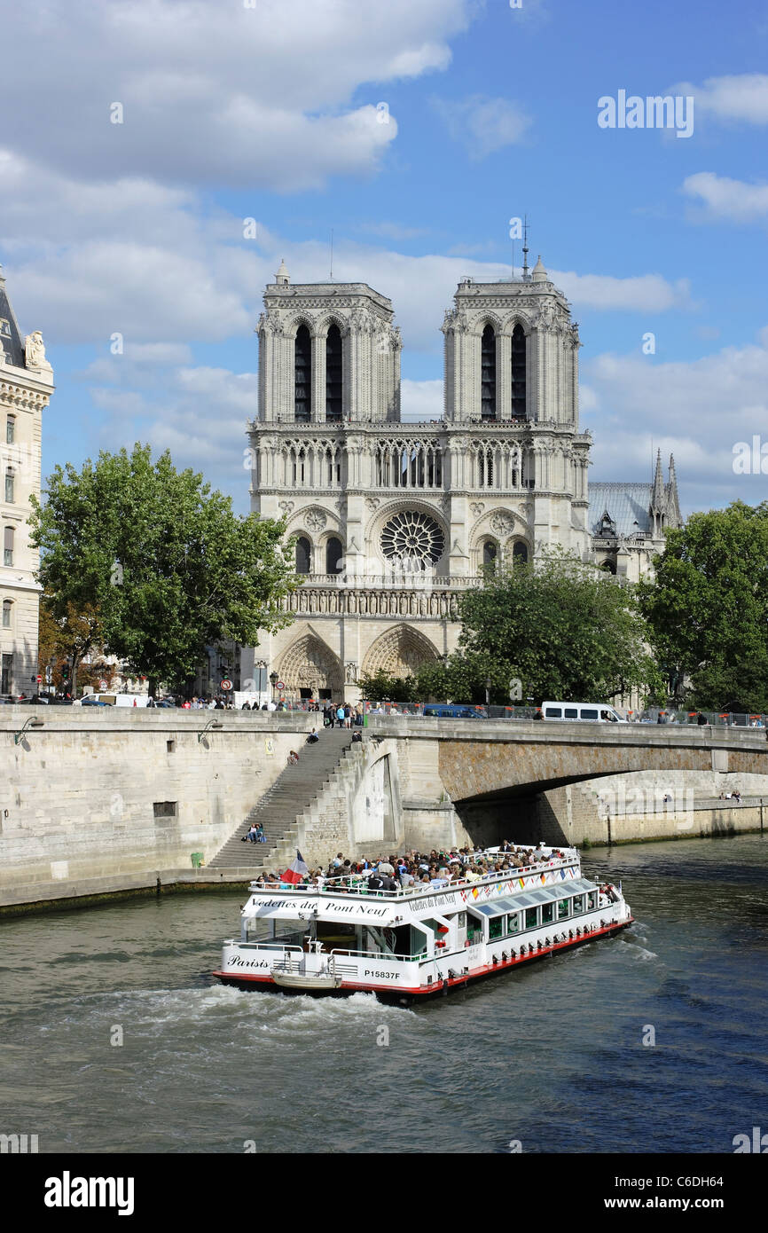 A pleasure boat cruising down the River Seine in Paris, just about to pass Notre Dame Cathedral Stock Photo