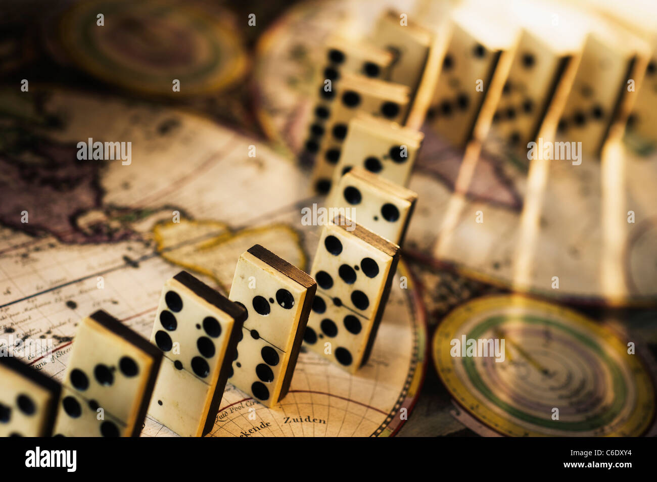Row of dominoes on old world map Stock Photo