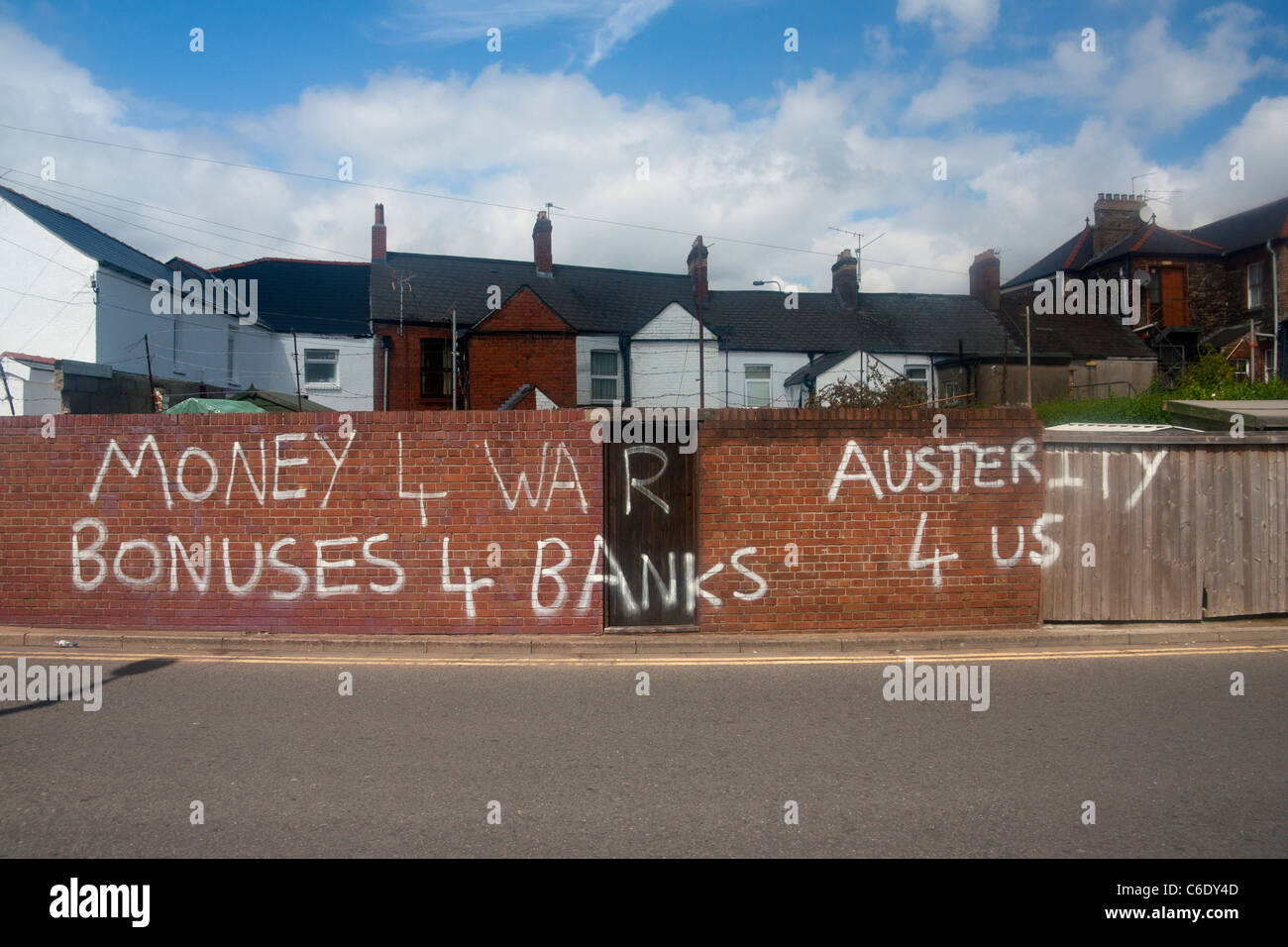 Political graffiti condemning economic policy Money 4 War Bonuses 4 Banks Austerity 4 Us White paint on red brick wall Stock Photo