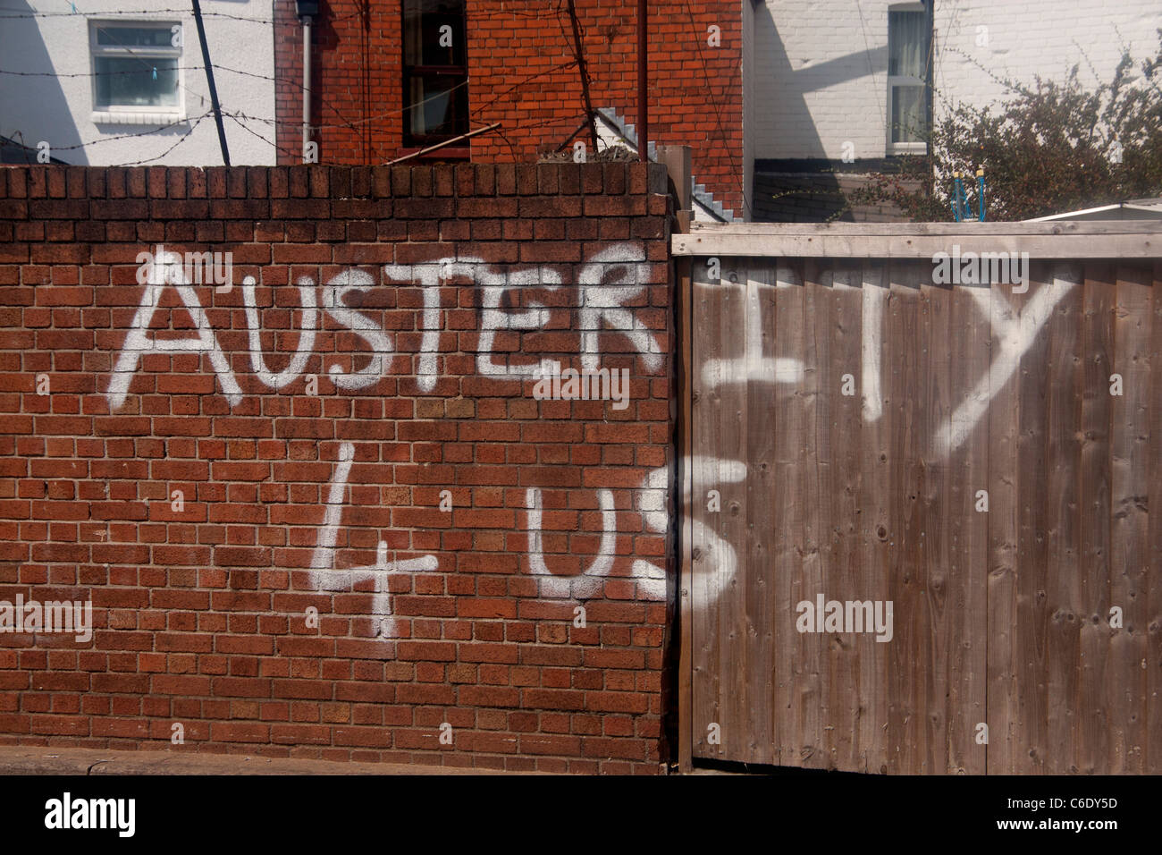 Graffiti condemning economic policy Money 4 War Bonuses 4 Banks Austerity 4 Us White paint on red brick wall Cardiff Wales UK Stock Photo