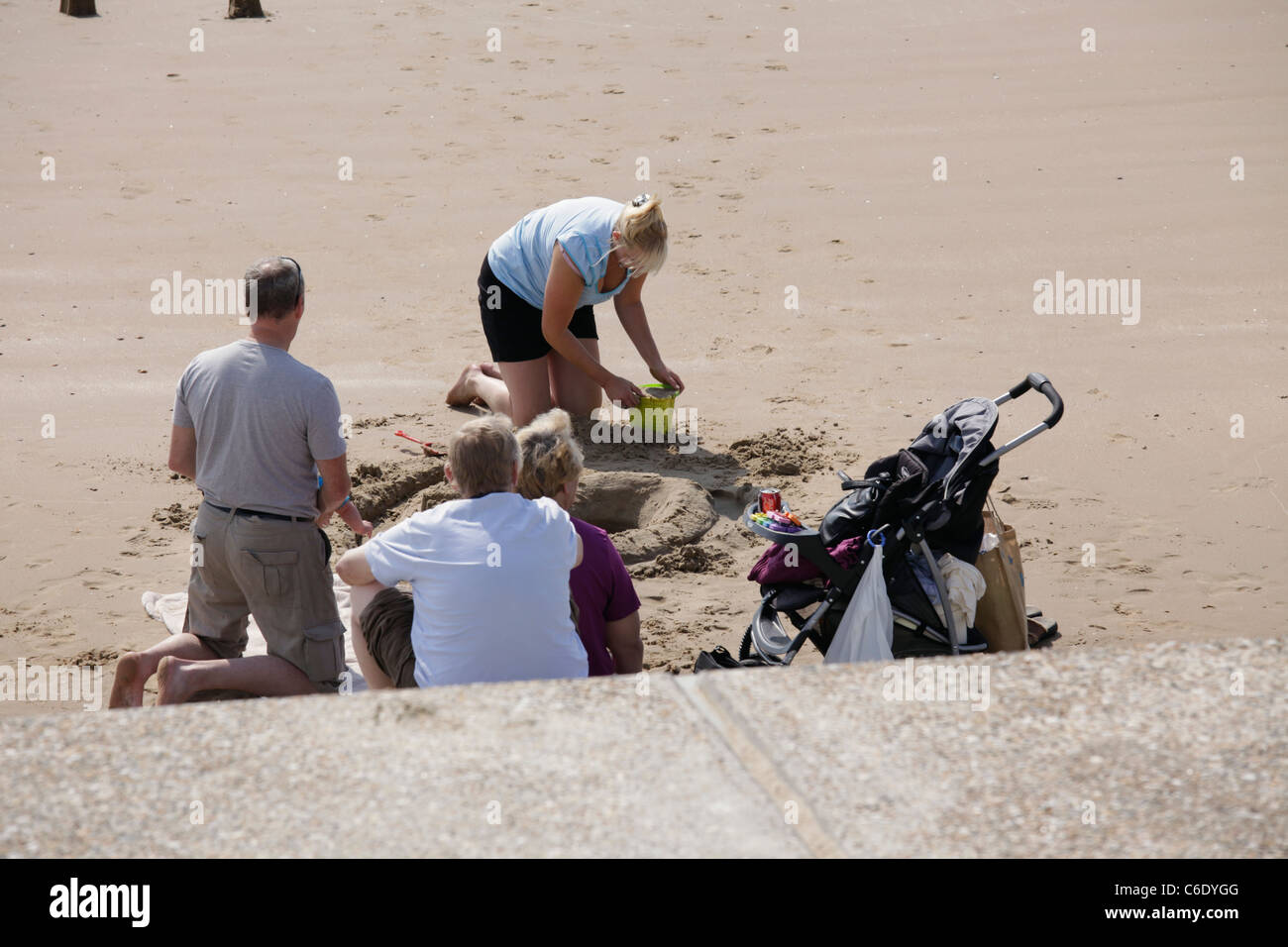 Adults building sand castles on Dymchurch beach Kent Stock Photo