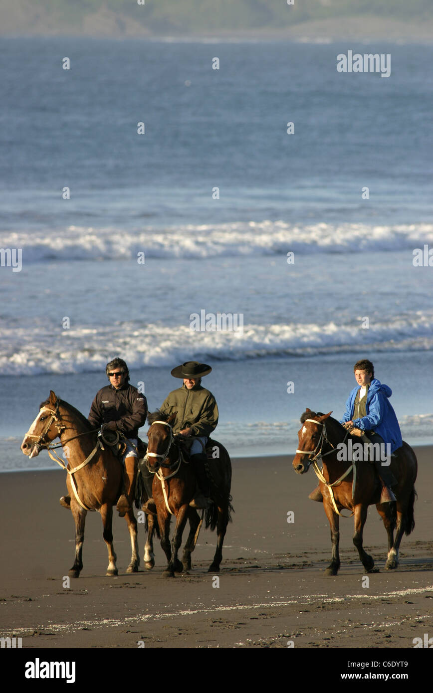 Horseback riding on the sandy Pacific Ocean beach. Pichilemu, Libertador General Bernardo O'Higgins, Chile, South America Stock Photo