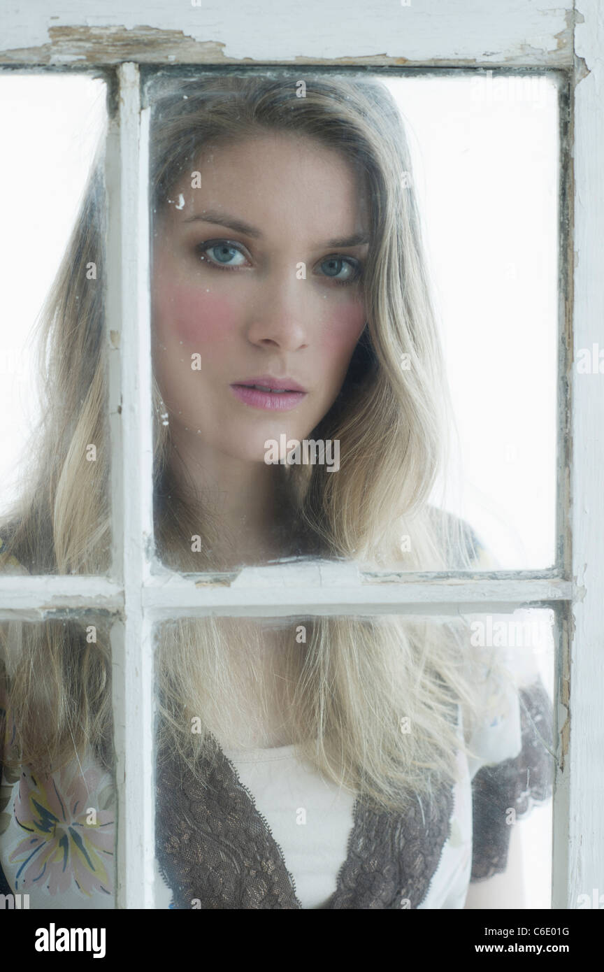 Portrait of young woman looking through window Stock Photo
