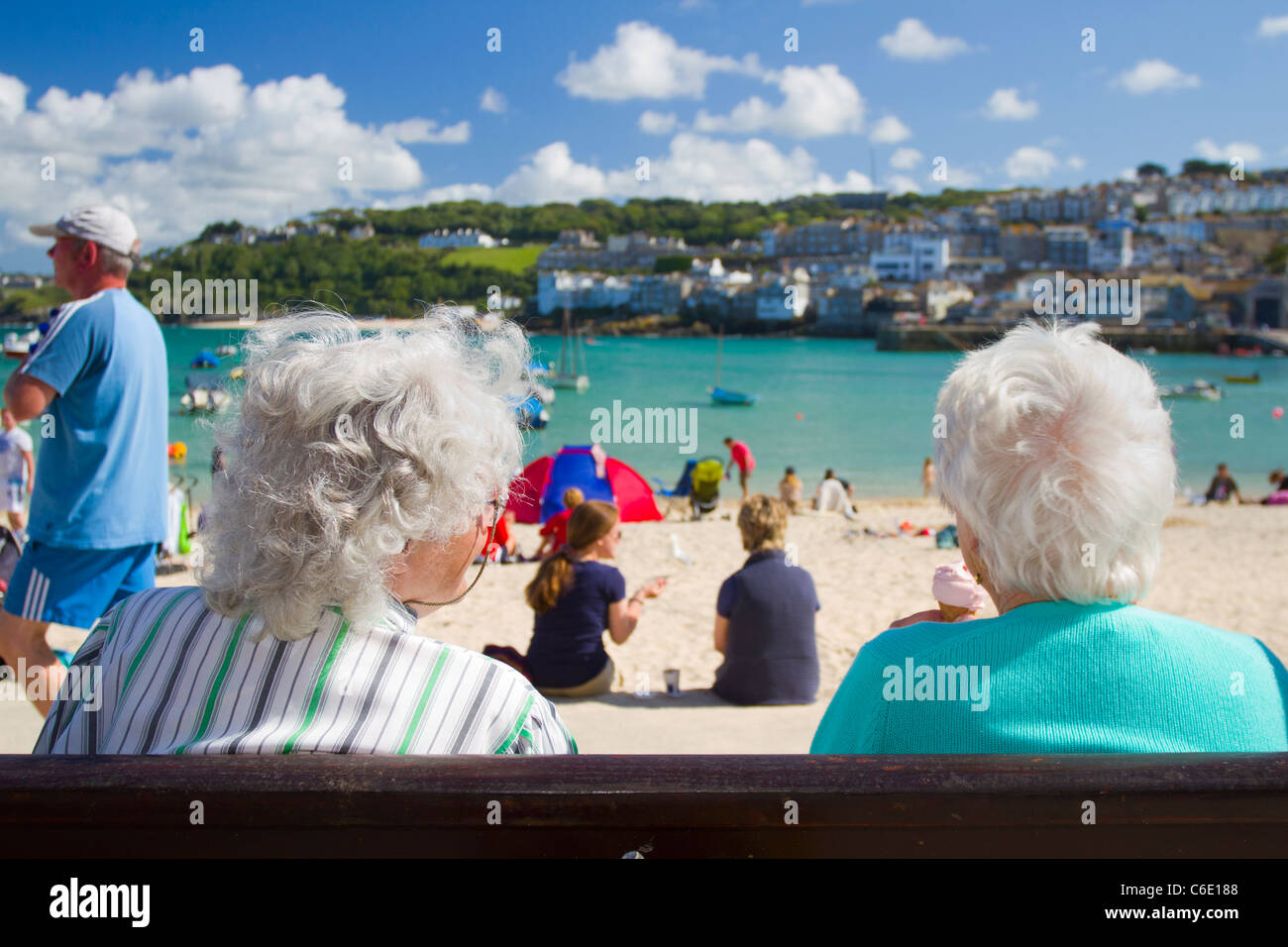 Two pensioners sit on a bench over looking St Ives' Harbour Beach. Stock Photo