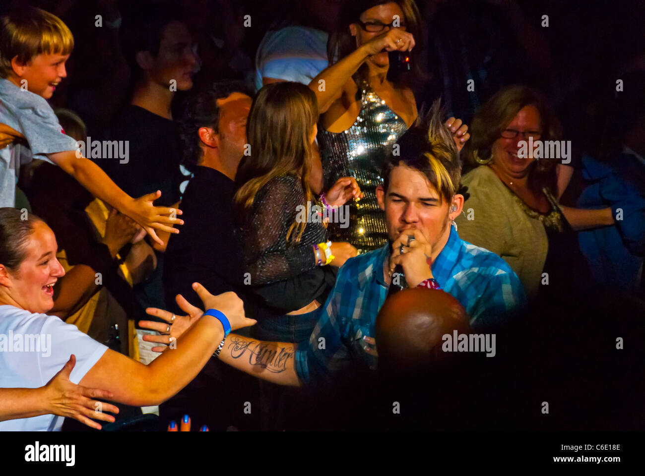 James Durbin singing, arm tattoo seen, lit by spotlight, walking among fans, American Idol Season 10 Concert, NY 2011 Stock Photo