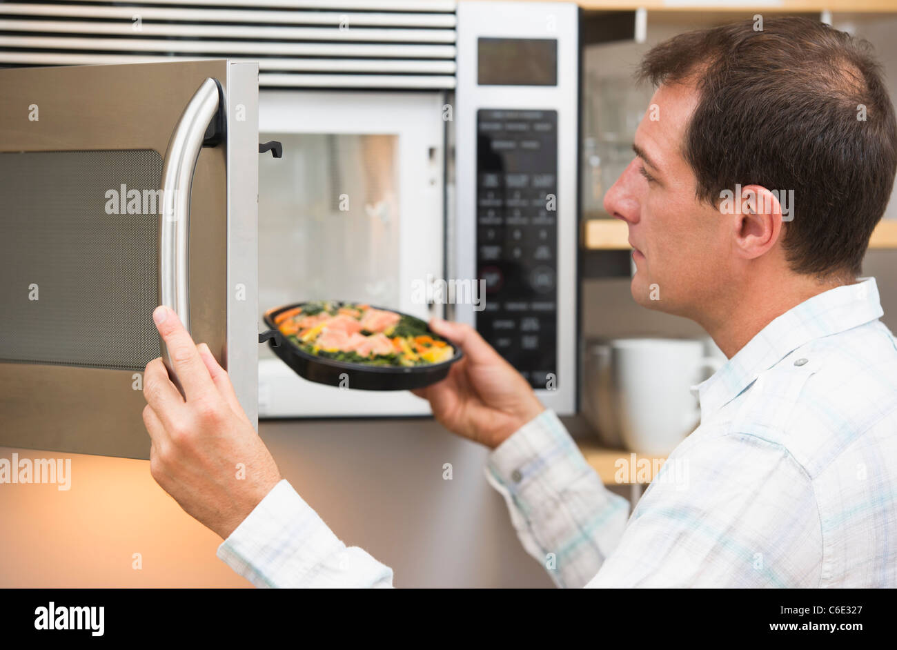 USA, New Jersey, Jersey City, Man inserting meal in microwave oven Stock Photo